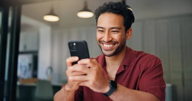 A customer smiling at a loan approval notification on their phone